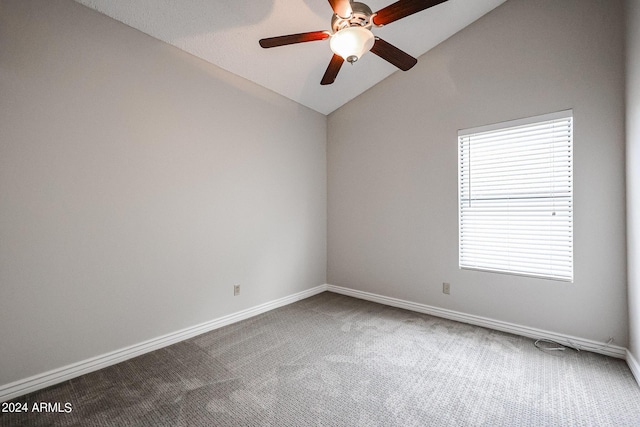 carpeted spare room with a ceiling fan, vaulted ceiling, and baseboards