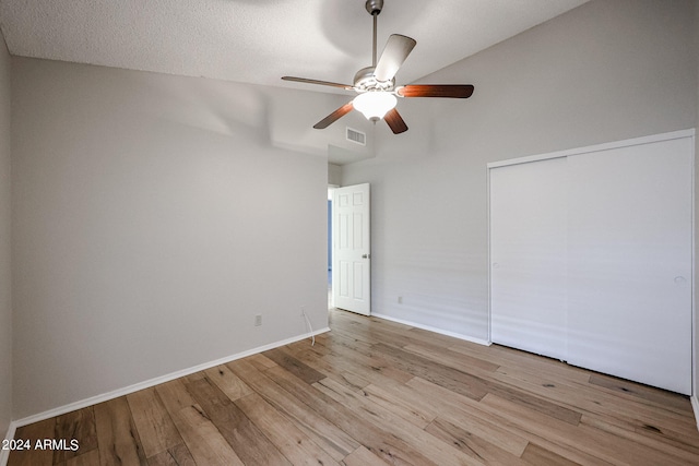 spare room with vaulted ceiling, a textured ceiling, ceiling fan, and light hardwood / wood-style floors