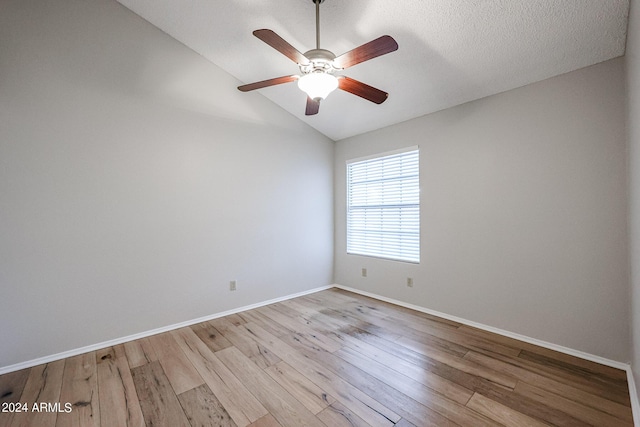 unfurnished room with lofted ceiling, a textured ceiling, wood finished floors, a ceiling fan, and baseboards