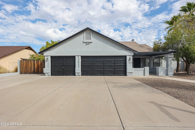 ranch-style house featuring an attached garage, fence, and concrete driveway