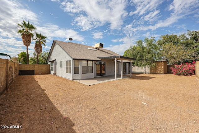 rear view of house with a fenced backyard, a shingled roof, an outdoor structure, stucco siding, and a patio area