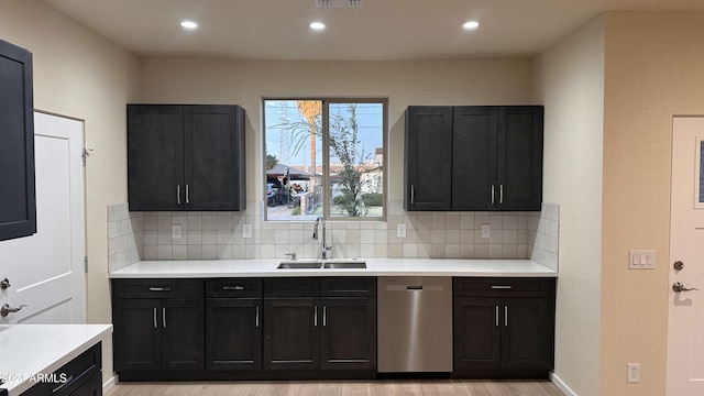 kitchen with tasteful backsplash, dishwasher, sink, and light hardwood / wood-style flooring