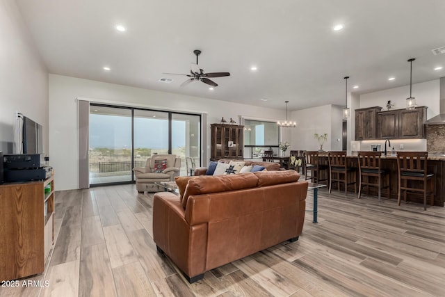 22050 W El Grande Trl, Wickenburg, AZ 85390 - living room with light wood-style flooring, ceiling fan with notable chandelier, visible vents, and recessed lighting
