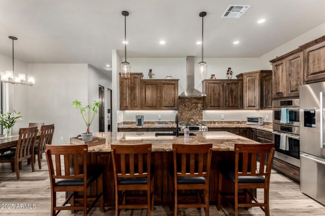 22050 W El Grande Trl, Wickenburg, AZ 85390 - kitchen with appliances with stainless steel finishes, wall chimney range hood, light stone counters, and visible vents