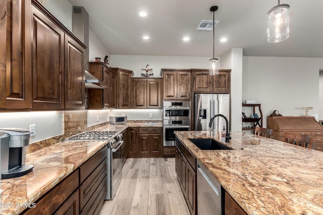 22050 W El Grande Trl, Wickenburg, AZ 85390 - kitchen with visible vents, light stone counters, a sink, stainless steel appliances, and light wood finished floors