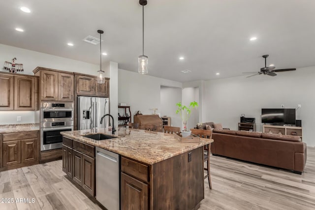22050 W El Grande Trl, Wickenburg, AZ 85390 - kitchen featuring visible vents, a sink, appliances with stainless steel finishes, light wood finished floors, and a breakfast bar area