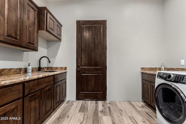22050 W El Grande Trl, Wickenburg, AZ 85390 - laundry area with washer / clothes dryer, light wood finished floors, a sink, and cabinet space
