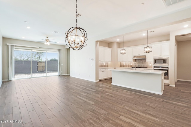 kitchen featuring pendant lighting, white cabinetry, wood-type flooring, and appliances with stainless steel finishes