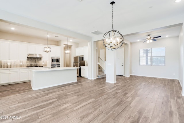 kitchen featuring a center island with sink, decorative light fixtures, light hardwood / wood-style floors, and appliances with stainless steel finishes