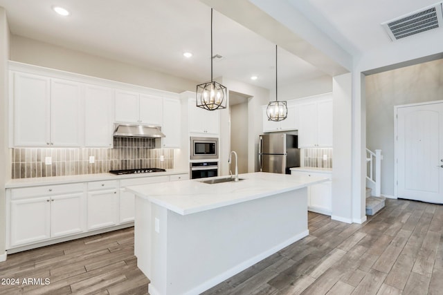 kitchen featuring white cabinetry, sink, stainless steel appliances, light hardwood / wood-style floors, and a kitchen island with sink