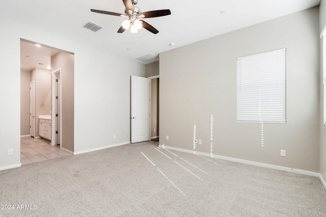 unfurnished bedroom featuring ceiling fan, light colored carpet, and connected bathroom