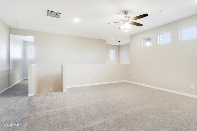 carpeted empty room with a wealth of natural light and ceiling fan