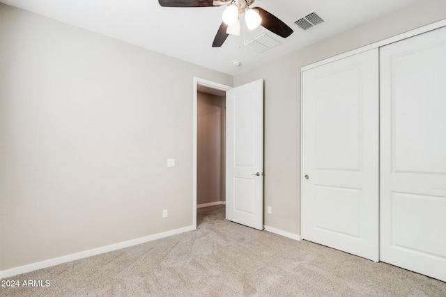 unfurnished bedroom featuring ceiling fan, a closet, and light colored carpet