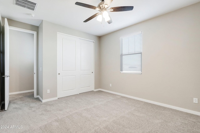 unfurnished bedroom with light carpet, a closet, and ceiling fan