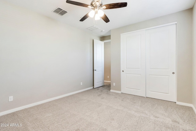 unfurnished bedroom with ceiling fan, a closet, and light carpet