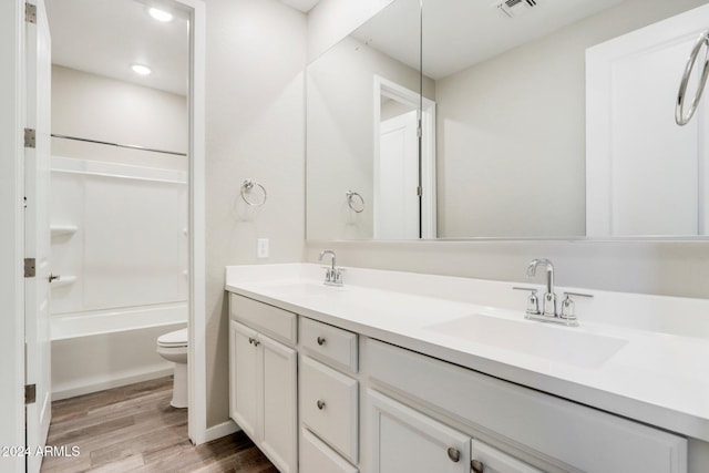 full bathroom with vanity, toilet, wood-type flooring, and washtub / shower combination