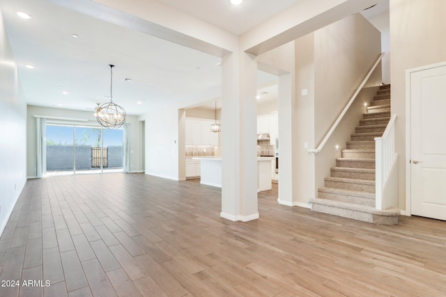 unfurnished living room with light hardwood / wood-style floors and an inviting chandelier