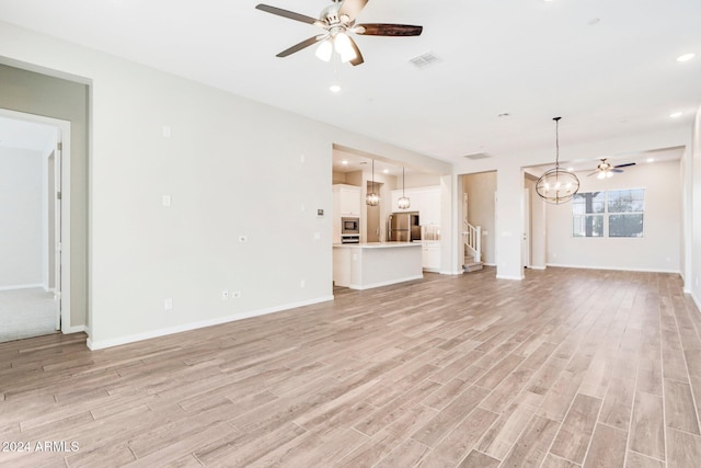 unfurnished living room with light hardwood / wood-style flooring and ceiling fan with notable chandelier