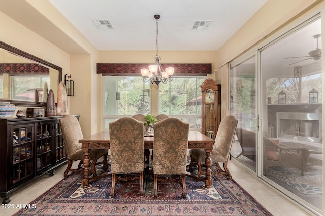 tiled dining space featuring ceiling fan with notable chandelier