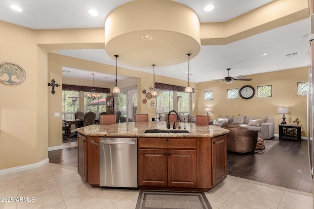 kitchen with a center island with sink, sink, stainless steel dishwasher, and decorative light fixtures