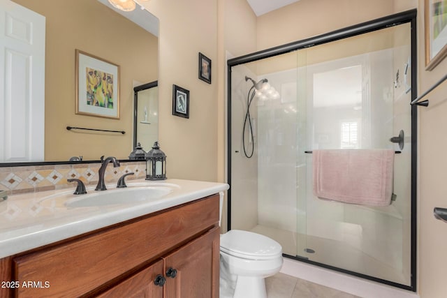 bathroom with a shower with door, vanity, tile patterned floors, and toilet