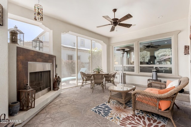 sunroom / solarium with ceiling fan and an outdoor fireplace