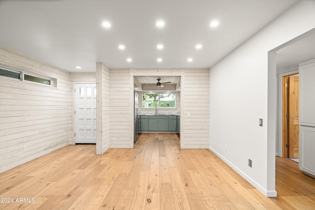 unfurnished living room featuring light hardwood / wood-style floors and wooden walls