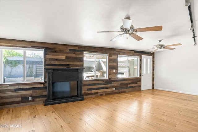 unfurnished living room with light hardwood / wood-style floors, plenty of natural light, and wood walls