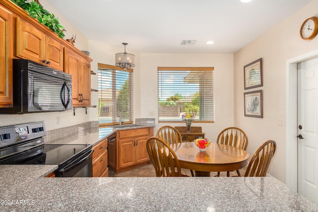 kitchen featuring hanging light fixtures, light tile patterned floors, light stone countertops, black appliances, and sink