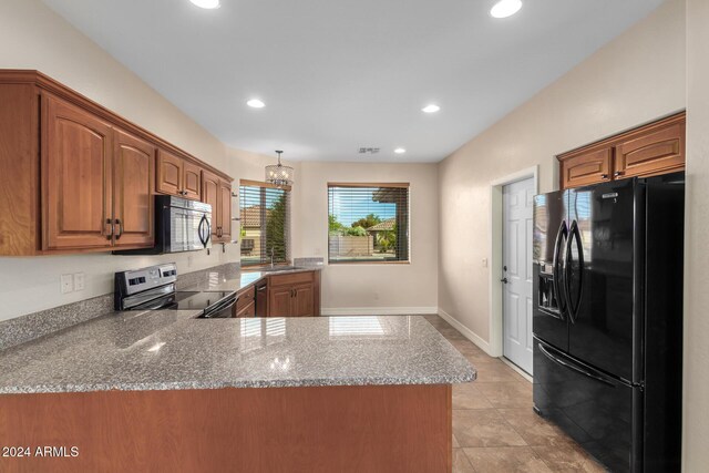 kitchen featuring light stone counters, a notable chandelier, black appliances, and sink