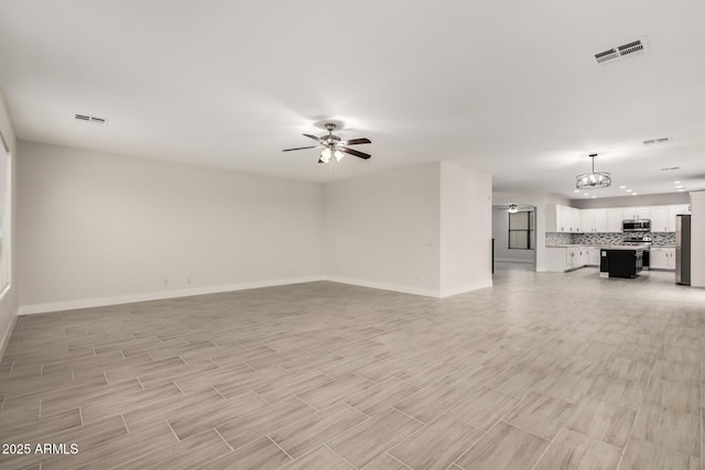 unfurnished living room with ceiling fan with notable chandelier and light wood-type flooring