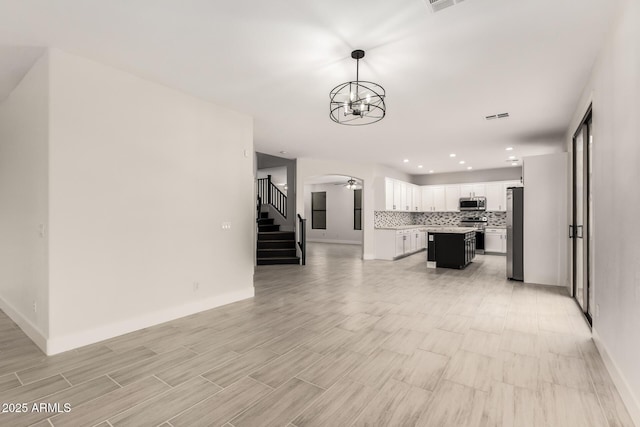 unfurnished living room with ceiling fan with notable chandelier