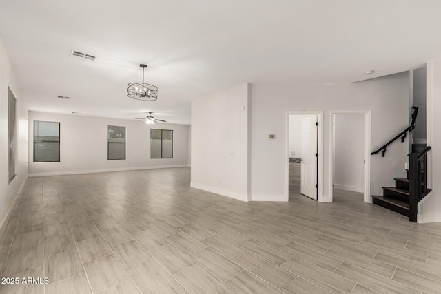 unfurnished living room with ceiling fan with notable chandelier