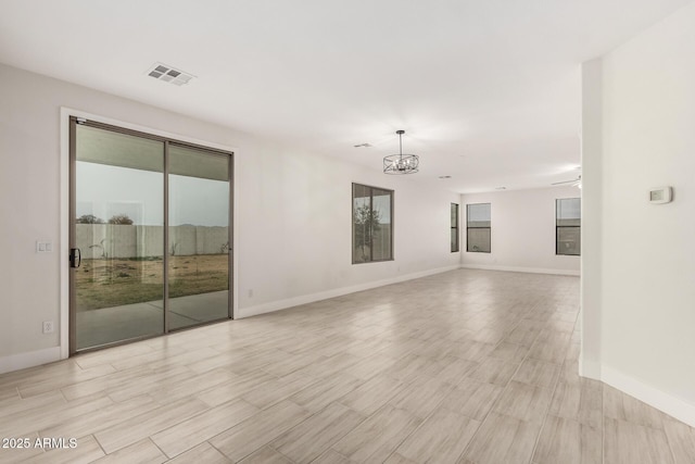 empty room featuring light hardwood / wood-style flooring and a notable chandelier