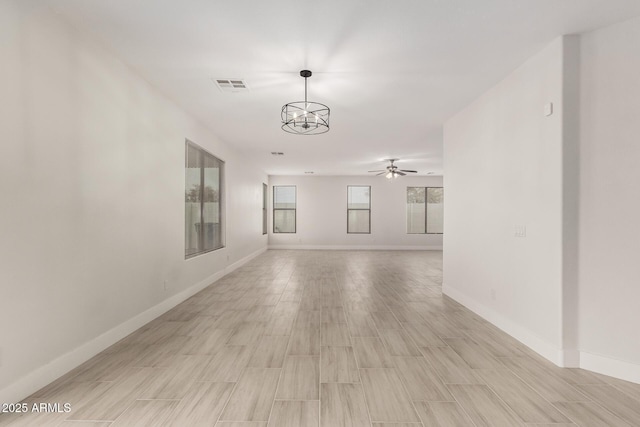 unfurnished room with ceiling fan with notable chandelier and light hardwood / wood-style flooring