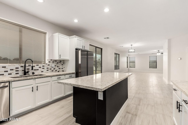 kitchen with sink, stainless steel appliances, a center island, and white cabinets