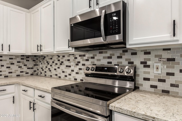 kitchen with stainless steel appliances, light stone countertops, white cabinets, and decorative backsplash