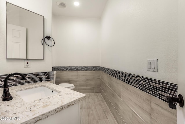 bathroom with vanity, tile walls, and toilet