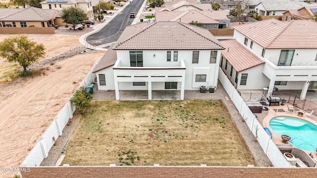 rear view of house featuring a fenced in pool and a patio area