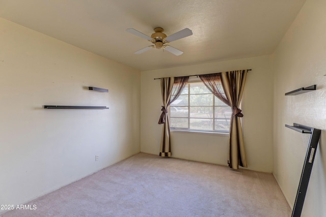 empty room with a ceiling fan and light colored carpet