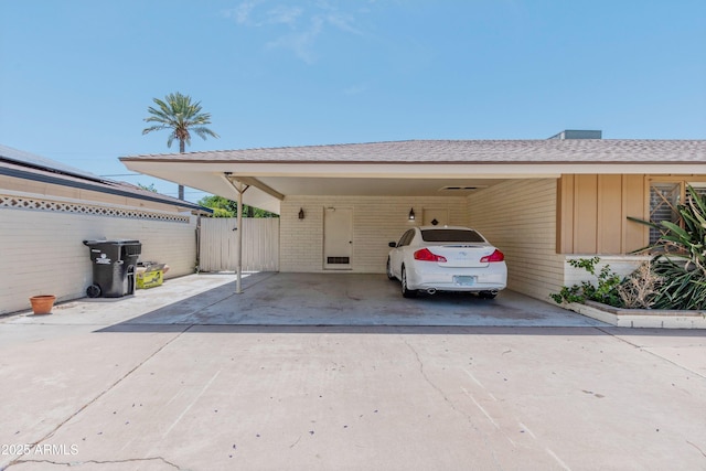 exterior space featuring fence, a carport, concrete driveway, and brick siding