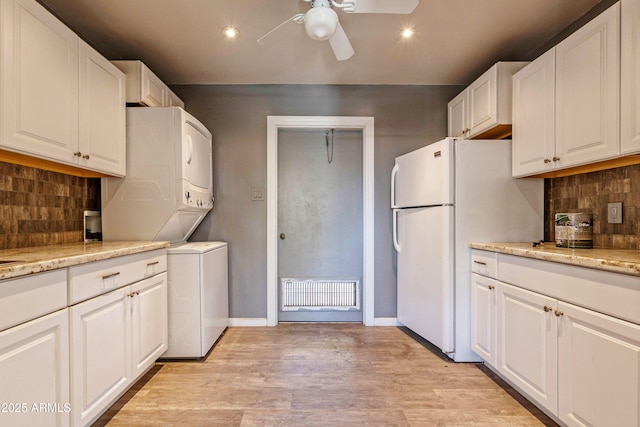 kitchen with a ceiling fan, stacked washer / drying machine, white cabinets, freestanding refrigerator, and recessed lighting
