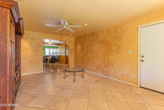 empty room with baseboards, a ceiling fan, and light tile patterned flooring