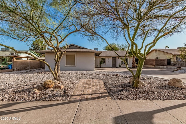 single story home featuring concrete driveway, brick siding, and fence