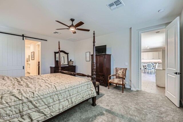 carpeted bedroom with ceiling fan, ensuite bathroom, and a barn door