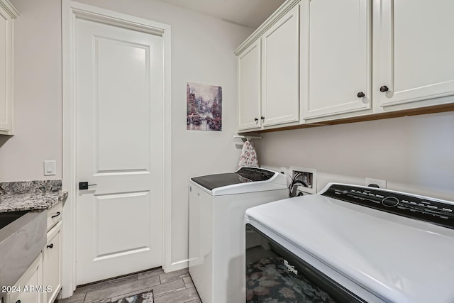 laundry room with light hardwood / wood-style flooring, independent washer and dryer, and cabinets