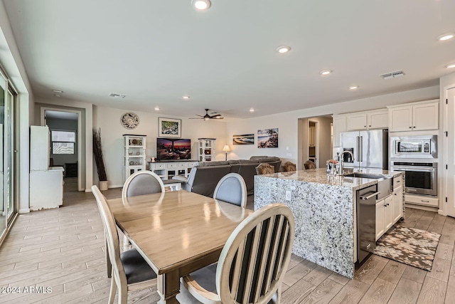 dining area featuring sink, light hardwood / wood-style floors, and ceiling fan