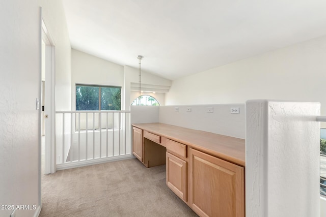 6510 S Hazelton Ln Unit 101, Tempe, AZ 85283 - kitchen with lofted ceiling, light carpet, light brown cabinetry, built in study area, and light countertops