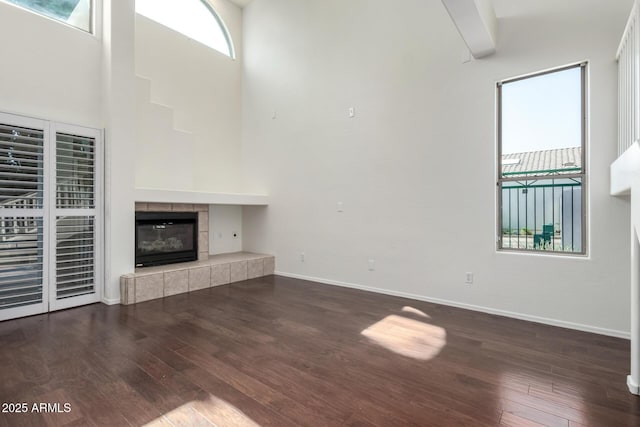 6510 S Hazelton Ln Unit 101, Tempe, AZ 85283 - unfurnished living room featuring wood finished floors, a fireplace, and a towering ceiling