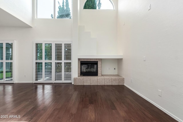 6510 S Hazelton Ln Unit 101, Tempe, AZ 85283 - unfurnished living room with plenty of natural light, a towering ceiling, wood finished floors, and a tiled fireplace